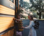Two young children getting on a school bus in their neighborhood.