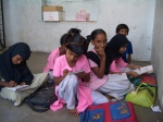 Children sitting together on the floor doing school work in a developing area of the world.